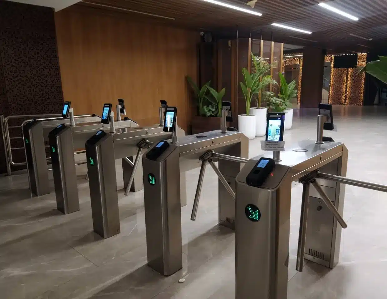 A row of turnstiles with face readers in an office lobby