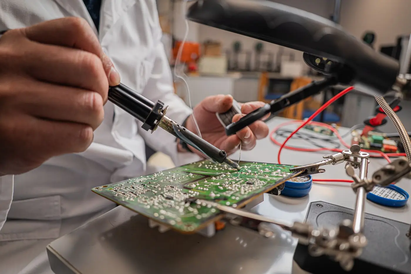 An engineer soldering a circuit board at a workbench